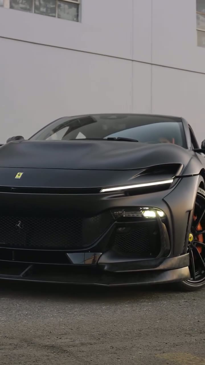 Matte black Ferrari Purosangue with a widebody kit and a red interior, filmed outside the shop