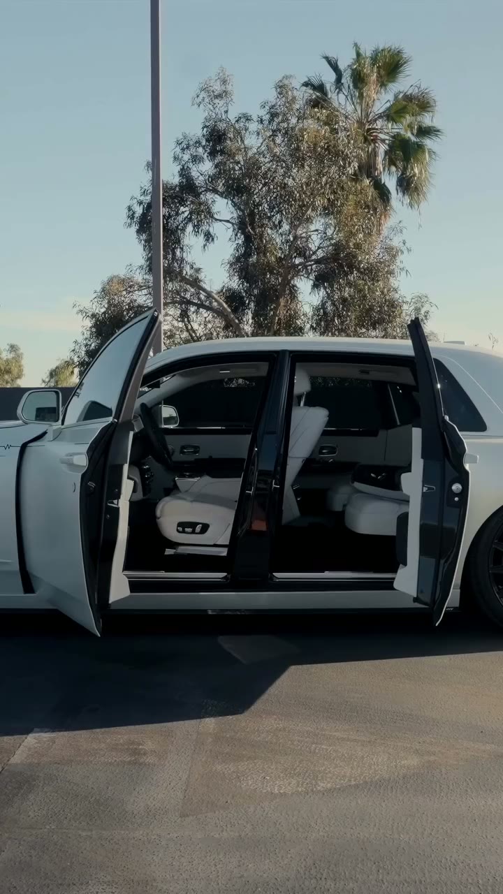 Satin white Rolls-Royce Ghost with black accents and a white interior, doors open