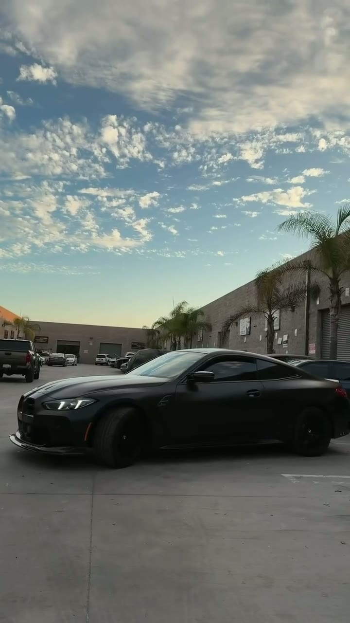 Matte black BMW M4 with a red interior, filmed outside the shop at dusk