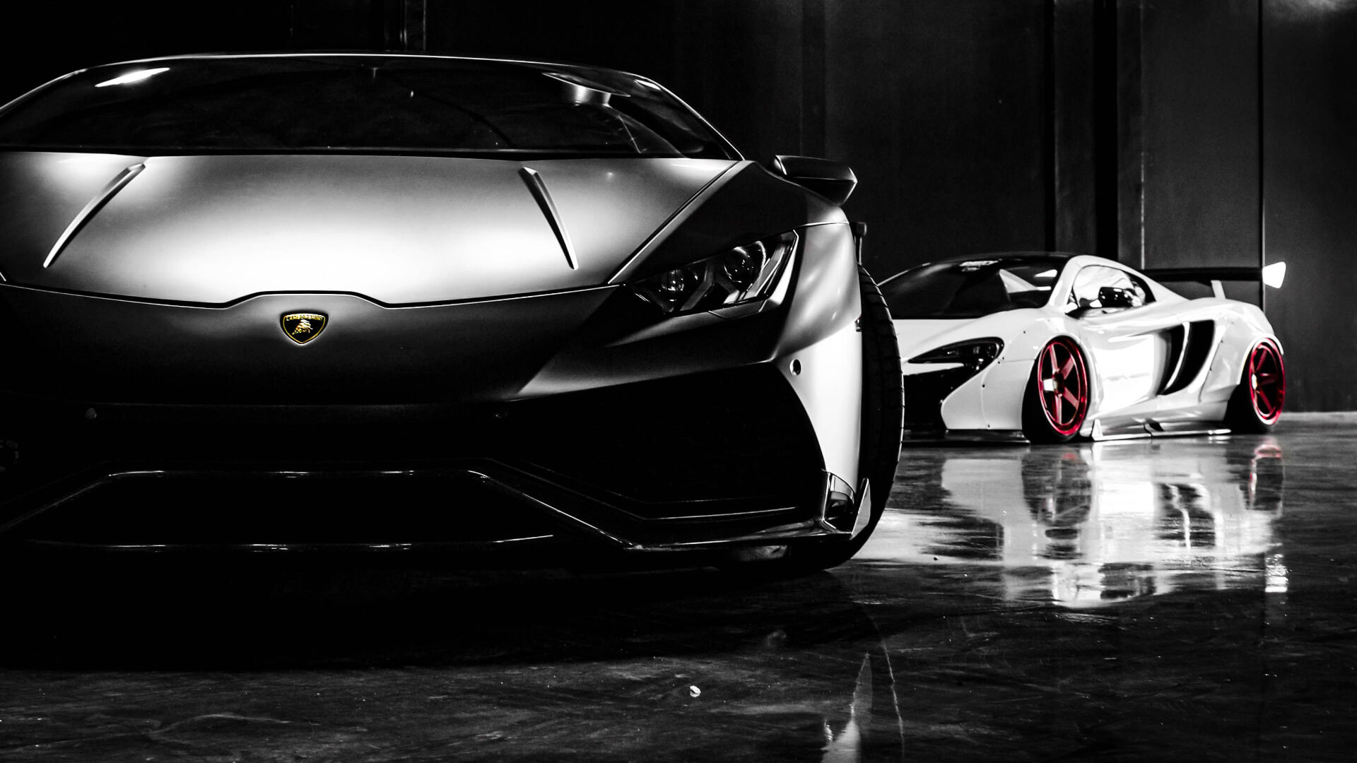 Two wrapped supercars parked side by side in a dark studio