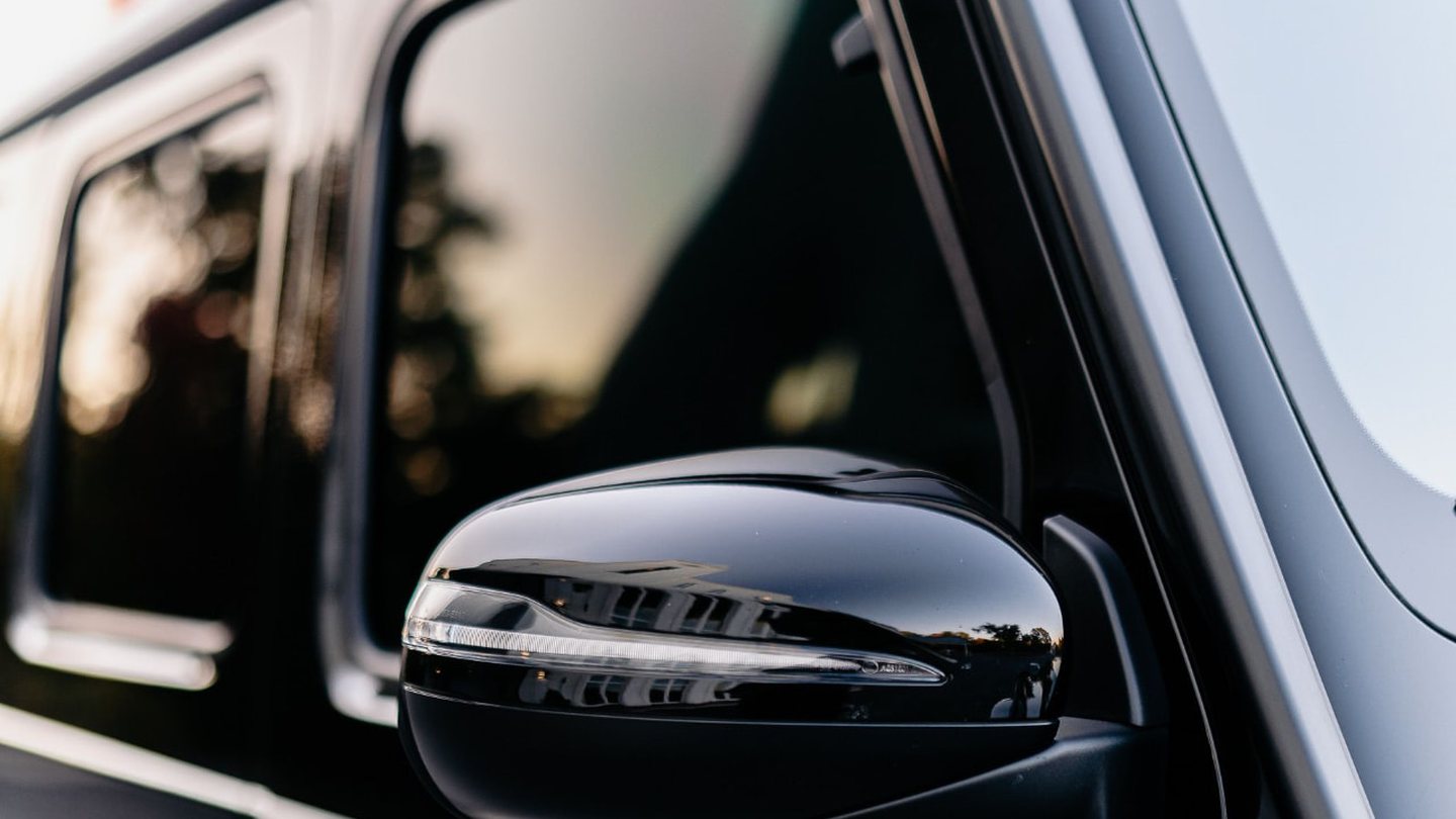 Tinted side windows and mirror on a glossy black luxury SUV